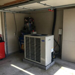 A garage air conditioner unit placed inside a garage near a shelf with tools and fluids.