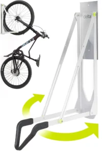 A close-up of the silver Delta pivot wall bike rack, showing its articulated arm that holds a bike's front wheel and swings it closer to the wall.