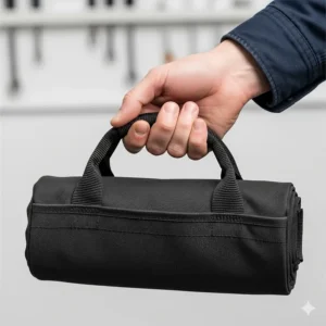 A person's hand holding a roll up tool bag by its carrying handle, emphasizing its portability and ergonomic design.