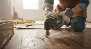 Close-up of an oscillating multi-tool performing a plunge cut into hardwood flooring during a home renovation.